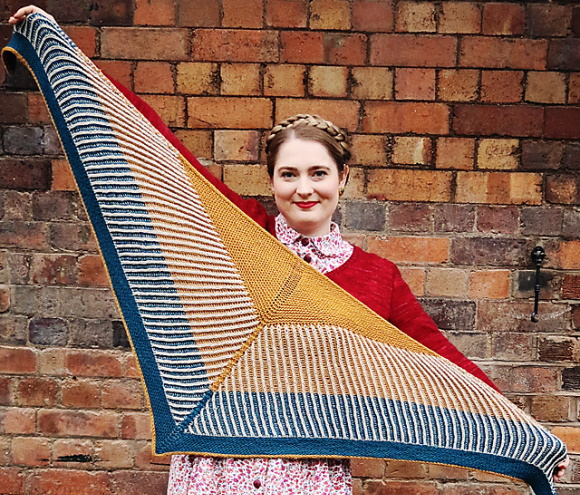 a woman holds a three colour shawl